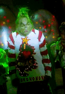 Gif of the grinch in a christmas sweater.