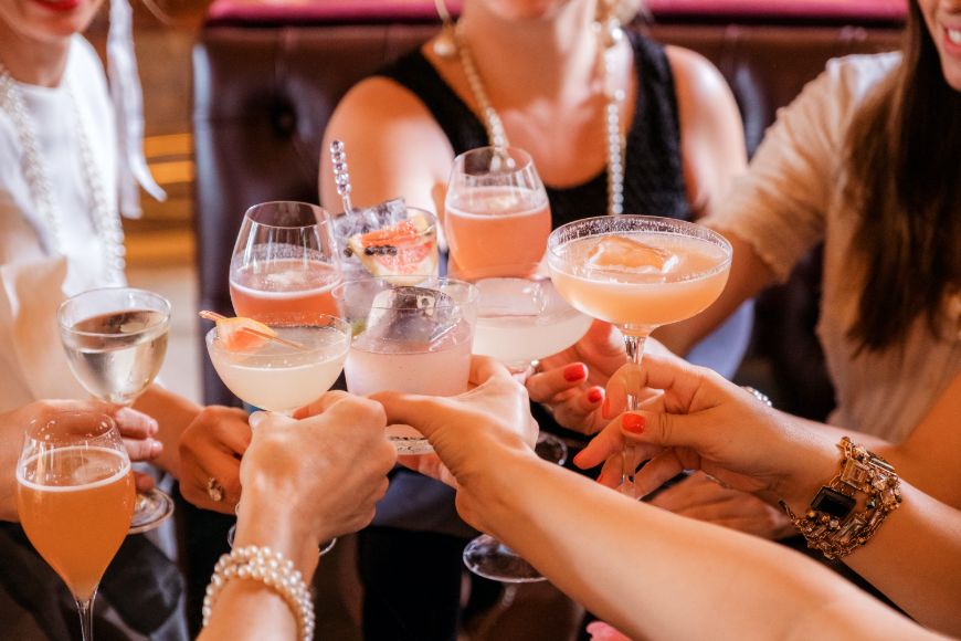 Several people cheersing with pink cocktails.